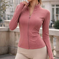 Woman wearing a fitted pink active jacket with zip front and long sleeves outdoors