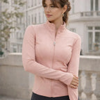 Woman wearing a fitted pink zip-up active jacket outdoors in an urban setting