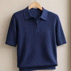 Navy textured knit polo shirt with short sleeves and collar on a wooden hanger
