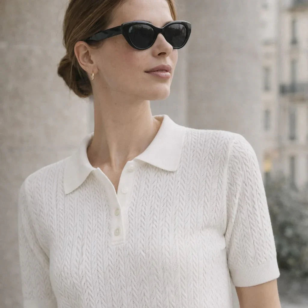 Woman wearing white textured knit polo shirt and black sunglasses outdoors
