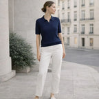 Woman wearing navy knit polo shirt and white pants standing outdoors in an urban setting