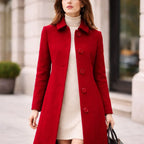 Woman wearing a red wool long coat over a cream sweater dress outdoors