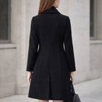 Woman wearing a black long wool coat with tailored fit, outdoor city setting, rear view