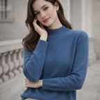 Woman wearing a blue high-neck jumper, posing outdoors near stone railing
