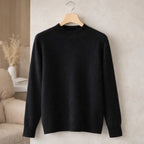 Black high-neck jumper with long sleeves on hanger against beige wall