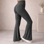 Woman wearing ribbed high-waisted flared pants in charcoal gray with white sneakers indoors