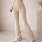 Woman wearing high-waisted beige ribbed knit flared pants and white sneakers indoors