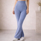 Woman wearing high-waisted ribbed knit flared blue pants and white sneakers indoors