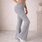 Woman wearing high-waisted grey ribbed knit flare pants in a minimal indoor setting