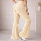 Woman wearing high-waisted beige ribbed knit flared pants, modern minimalist interior.