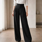 Woman wearing high-waisted black tailored wide-leg trousers and white shirt indoors