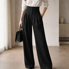 Woman wearing black high-waisted wide-leg tailored trousers and white shirt indoors