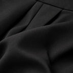 Close-up of black tailored wide-leg trousers fabric with fine texture and neat pleats