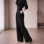 Woman wearing high-waisted black tailored wide-leg trousers in a modern room
