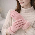 Woman wearing soft pink suede winter gloves with faux fur cuffs, cozy indoor setting