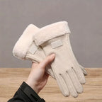 Beige winter gloves with faux fur cuffs held in hand on a wooden table background