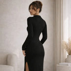 Woman in a fitted black ribbed V-neck long sleeve dress with side slit, indoor setting
