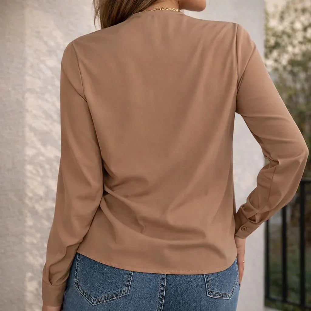 Back view of woman wearing tan long sleeve blouse and blue jeans outdoors