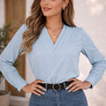 Woman wearing a light blue long sleeve blouse with V-neck and blue jeans