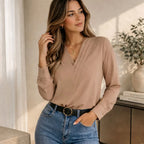 Woman wearing a beige soft drape V-neck blouse with long sleeves and high-waisted blue jeans